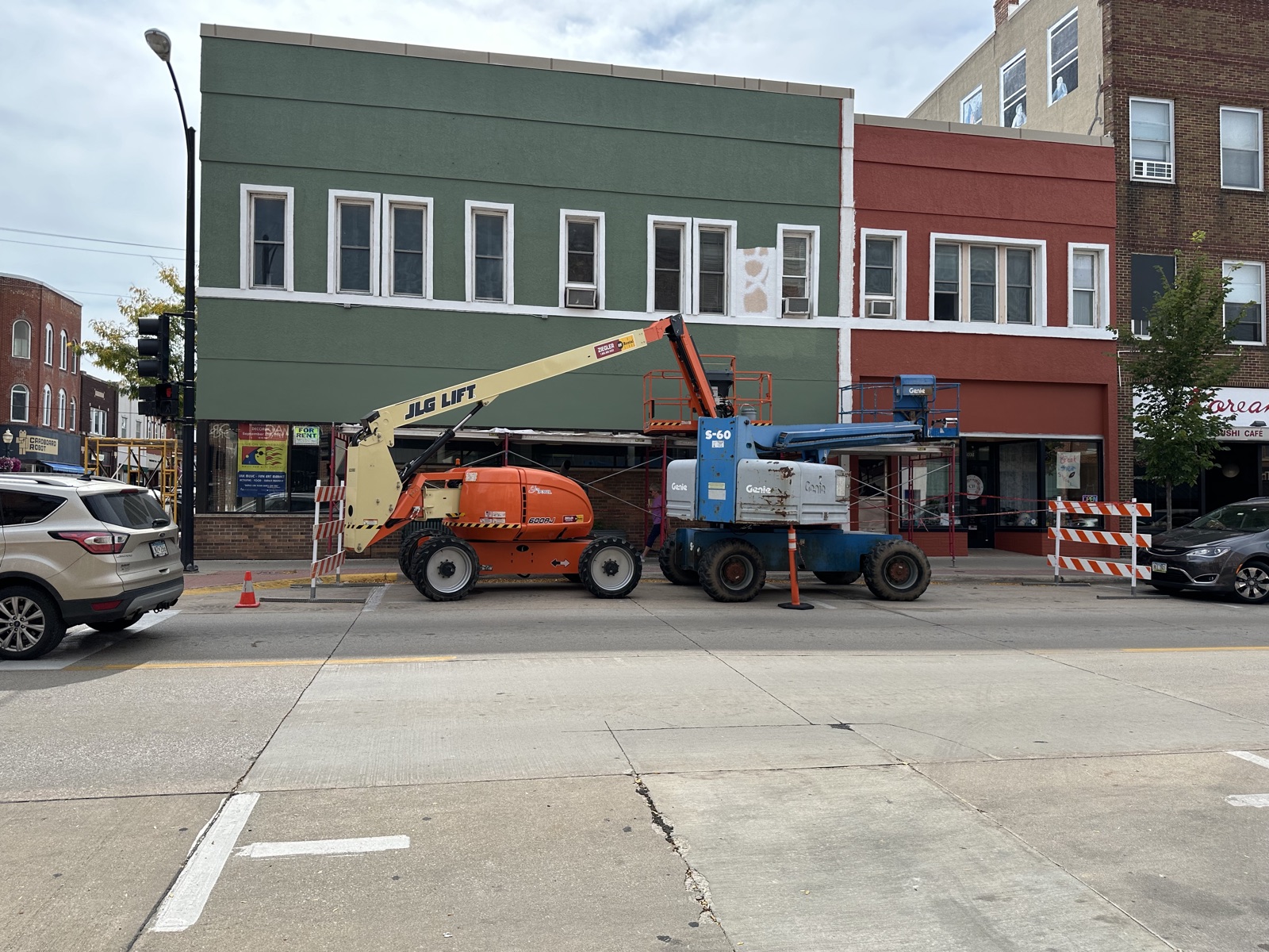 Downtown storefront with green and red scissor lifts on facade