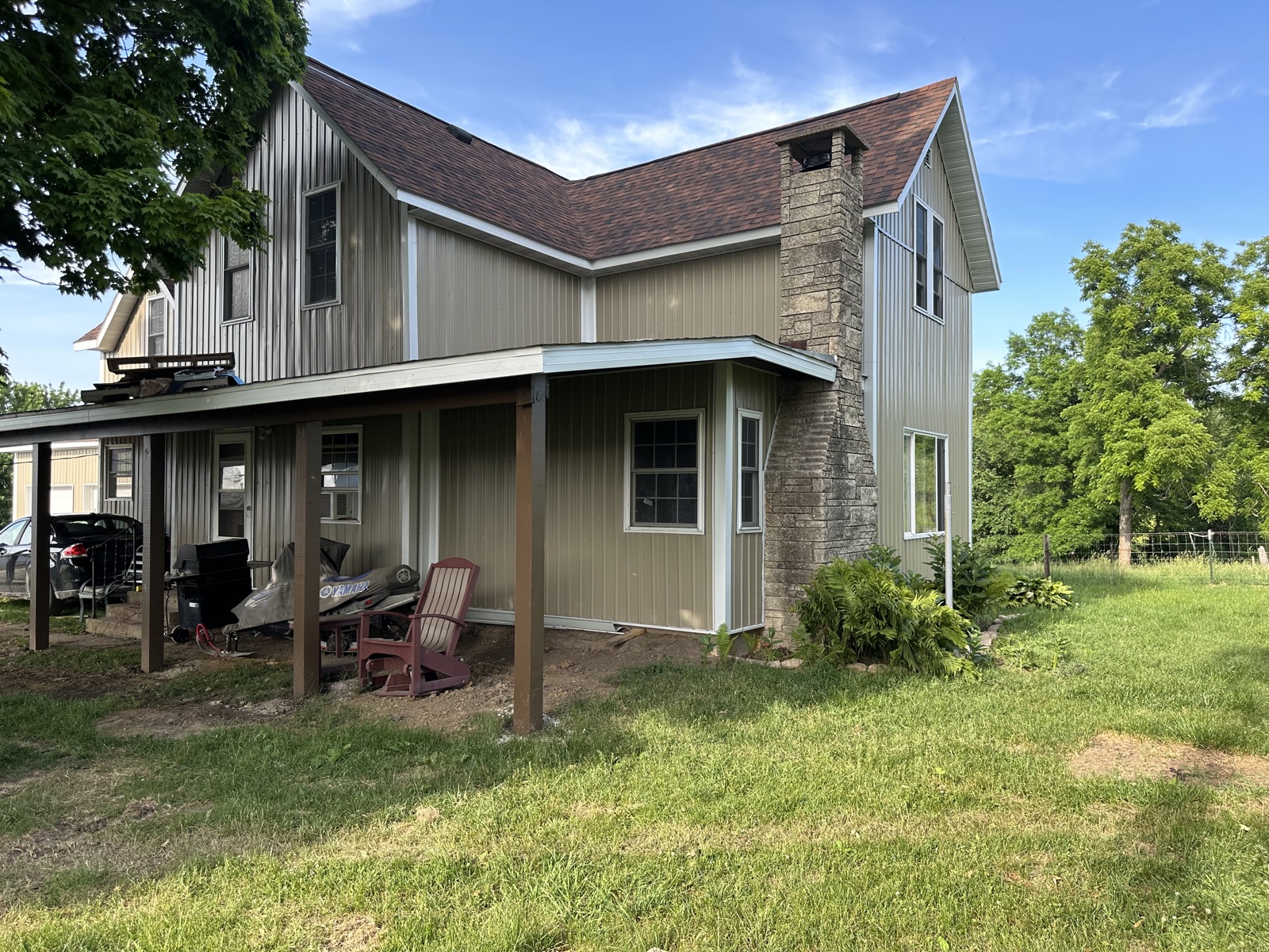 Farmhouse side view with stone chimney and porch