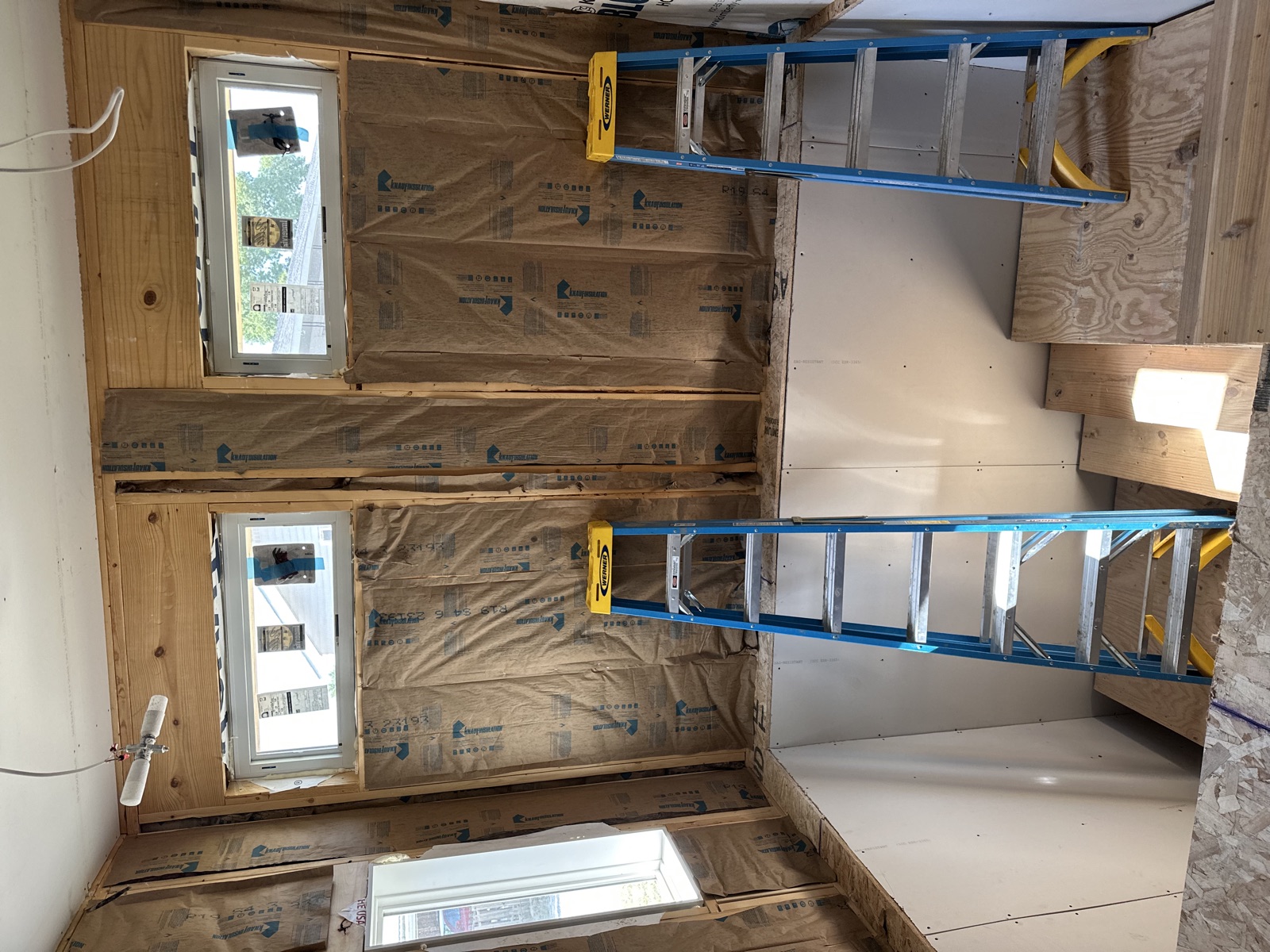Ceiling insulation install with blue ladders on jobsite