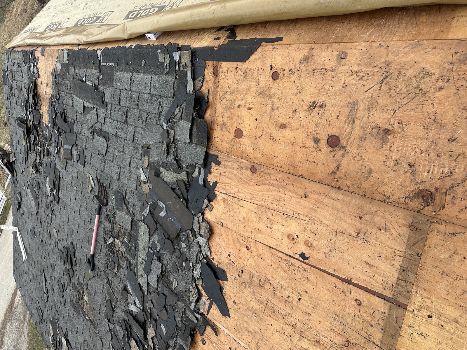 Roof tear-off with shingles removed and decking exposed